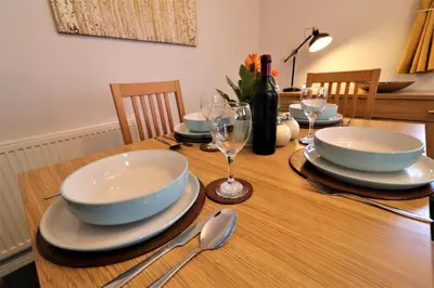 a wooden table with plates and bowls and wine glasses at Signature- Connelly House in Motherwell