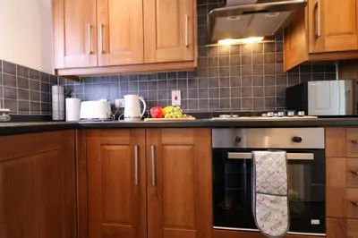 a kitchen with wooden cabinets and a stove top oven at Signature- Connelly House in Motherwell