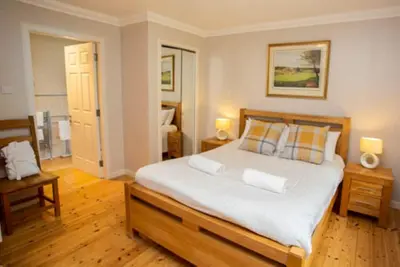 a bedroom with a large white bed with two lamps at Bonnie Banks Cottage in Balloch