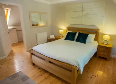 a bedroom with a bed with blue pillows on it at Bonnie Banks Cottage in Balloch