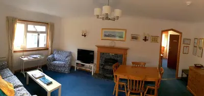 a living room with a table and a fireplace at Dalkell Cottages in Tyndrum