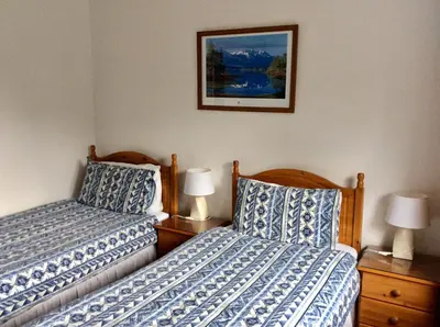 a bedroom with two beds and a picture on the wall at Dalkell Cottages in Tyndrum
