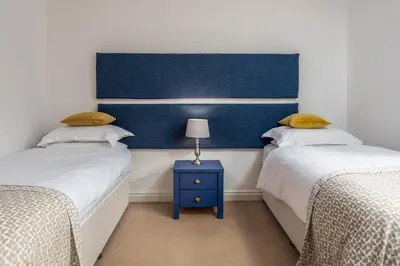 a bedroom with two beds and a blue headboard at Turnberry Serviced Apartments in Turnberry