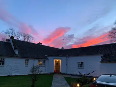 a white house with a sunset in the background at South Craighall B&B in Eaglesham
