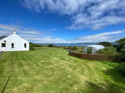 a white house in a field with a grass yard at Portbahn, Bruichladdich in Bruichladdich