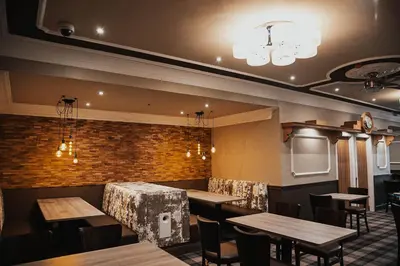 a restaurant with wooden tables and chairs and a brick wall at Mill & Brae in Paisley