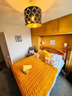 a bedroom with a large orange bed with a lamp at Park Road Holiday Home - Spacious 3 bedroom house with garden near Edinburgh in Rosyth