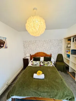 a bedroom with a bed with a green bedspread at Park Road Holiday Home - Spacious 3 bedroom house with garden near Edinburgh in Rosyth
