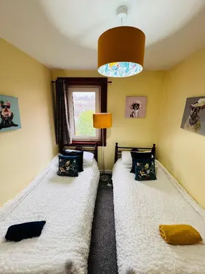 a bedroom with two beds and a lamp and a window at Park Road Holiday Home - Spacious 3 bedroom house with garden near Edinburgh in Rosyth