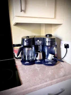 a counter top with a coffee maker and coffee pots at Park Road Holiday Home - Spacious 3 bedroom house with garden near Edinburgh in Rosyth