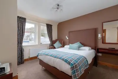 a bedroom with a large bed and a window at Kilchrenan House in Oban