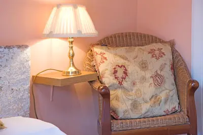 a wicker chair with a pillow next to a lamp at Kilchrenan House in Oban