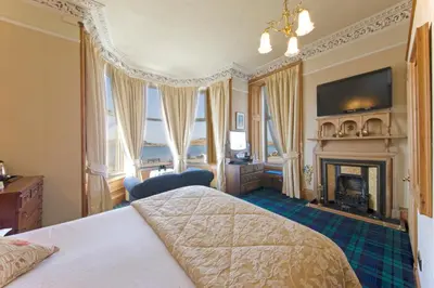 a bedroom with a bed and a fireplace and a television at Kilchrenan House in Oban