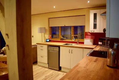 a kitchen with white cabinets and a stainless steel dishwasher at Tigh a Chabar in Lochaline