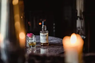 a bottle of whisky sitting on a table with a glass at Thackray House in Callander