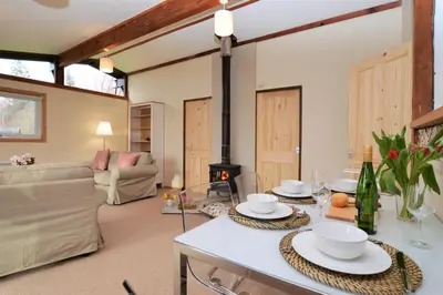 a living room with a table and a fireplace at Clamshell Lodge in Otter Ferry