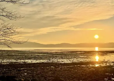 a sunset over the water with the sun in the sky at Clamshell Lodge in Otter Ferry