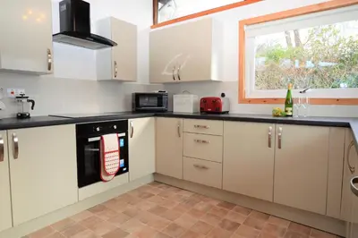a kitchen with white cabinets and a window at Clamshell Lodge in Otter Ferry