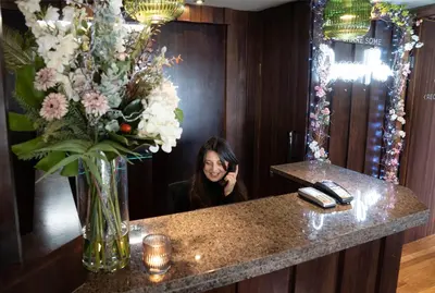a woman sitting at a counter with a vase of flowers at Orocco Pier in Queensferry