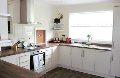 a kitchen with white cabinets and a large window at The Glebe, Am Fasgadh in Bowmore