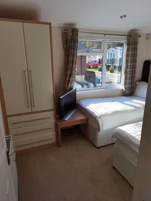 a bedroom with two beds and a dresser with a tv at Bonnie Banks Lodge Ardlui in Ardlui