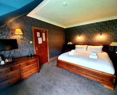 a bedroom with a large bed and a television at Achray House Restaurant with Rooms in Saint Fillans