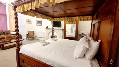 a bedroom with a wooden canopy bed with white pillows at The Guards Hotel in Edinburgh
