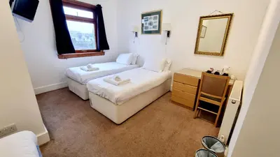 a small room with two beds and a mirror at The Guards Hotel in Edinburgh