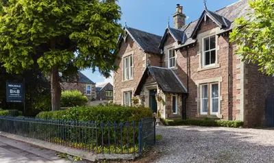a house with a fence in front of it at Merlindale in Crieff
