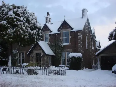 a house covered in snow with a fence at Merlindale in Crieff