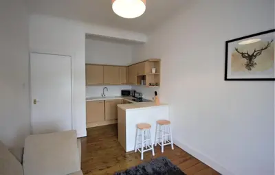 a kitchen with a counter and stools in a room at Bright and Cosy West End Apartment in Glasgow