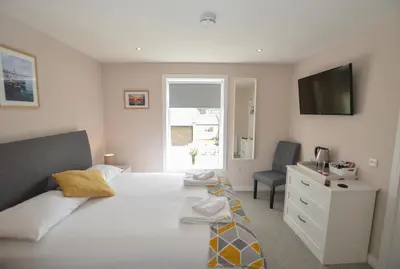 a bedroom with a bed and a television and a chair at Fairhaven, Oban Town Centre in Oban