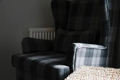 a plaid chair in a room with a radiator at Fairhaven, Oban Town Centre in Oban