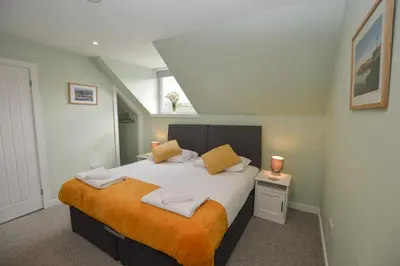 a bedroom with a large white bed with orange blanket at Fairhaven, Oban Town Centre in Oban
