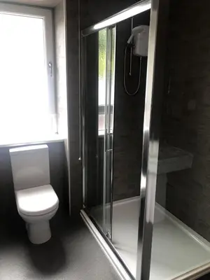 a bathroom with a toilet and a glass shower at Islay Frigate Hotel in Tarbert