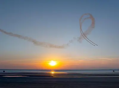 an airplane is flying over the beach at sunset at Arran View - Coorie Doon Stays in Ayr