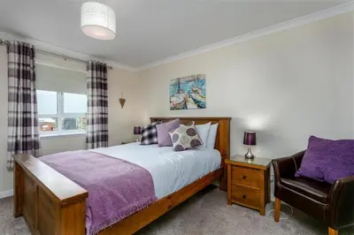 a bedroom with a bed and a chair at Arran View - Coorie Doon Stays in Ayr