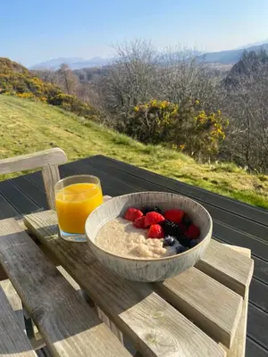a bowl of fruit on a wooden table with a glass of orange juice at Aspen Lodge in Oban