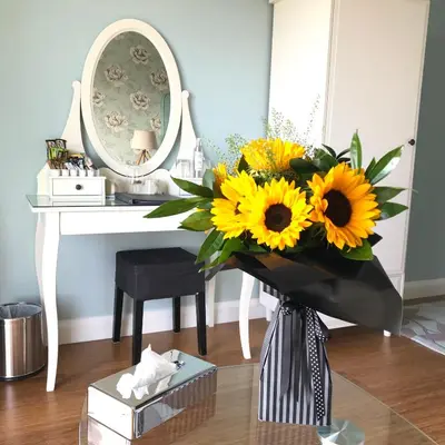 a vase filled with sunflowers in front of a desk at Aspen Lodge in Oban
