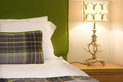 a bedroom with a bed and a lamp on a night stand at Aspen Lodge in Oban