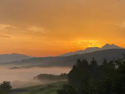 a misty valley with mountains in the background at sunset at Aspen Lodge in Oban