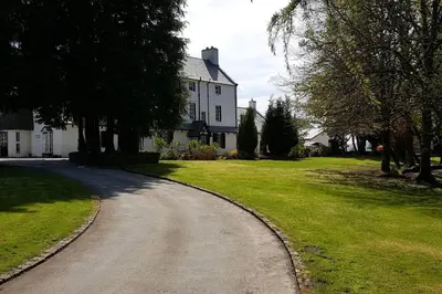 a winding road in front of a white house at Stuc an t Sagairt Cottage , Loch Lomond in Drymen
