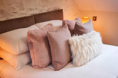 a pile of pillows sitting on top of a bed at Stuc an t Sagairt Cottage , Loch Lomond in Drymen