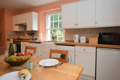 a kitchen with a table with a bowl of fruit on it at Rhoda`s Cottage in Creggans
