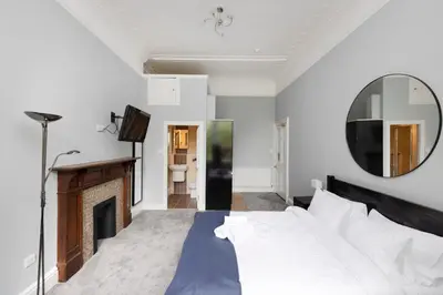 a bedroom with a bed and a mirror and a fireplace at JOIVY Haymarket in Edinburgh
