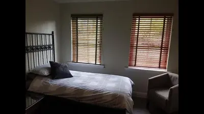 a bedroom with a bed and a chair and two windows at Luxury 2Bedroom Lodge in Auchterarder