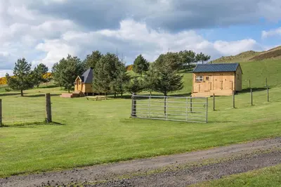 a barn and a house in a field at Little Lochan Lodge in Glenfarg