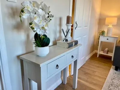 a white console table with a vase of flowers on it at Kintyre Apartment in Ayr