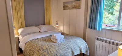 a small bedroom with a bed with two towels on it at Lochend Chalets in Port of Menteith