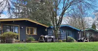 a blue house with chairs in front of it at Lochend Chalets in Port of Menteith